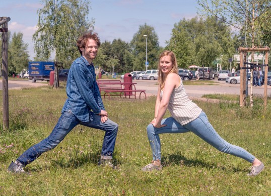 two people make stretch exercises on a meadow