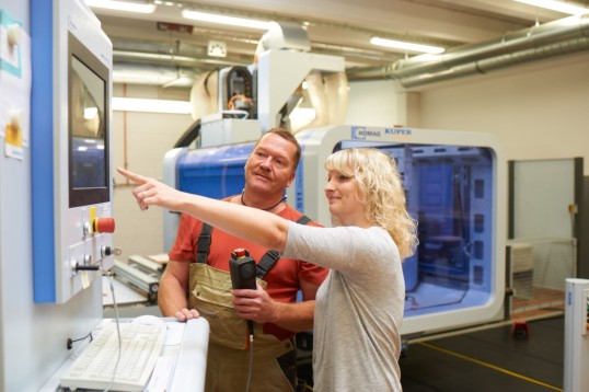 two persons in front of a machine