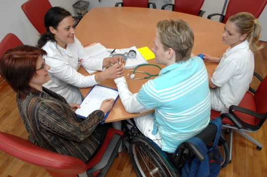 mehrere Personen sprechen mit dem Rehabilitanden