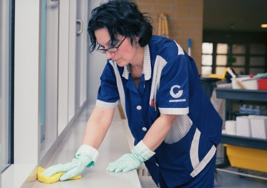 eine Frau putzt eine Fensterbank