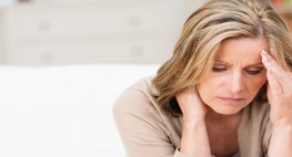 A woman looks down and puts her hand to her forehead