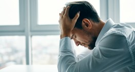 A man is resting his head on his hand and looking down.