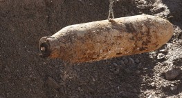 Eine rostige Bombe hängt an einem Drahtseil.