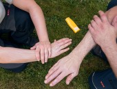 Zwei Männer cremen ihre Hände mit einem Sonnenschutzmittel ein