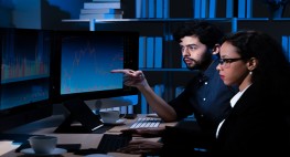 A man and a woman are sitting in a room in front of a screen.