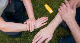 Zwei Männer cremen ihre Hände mit einem Sonnenschutzmittel ein