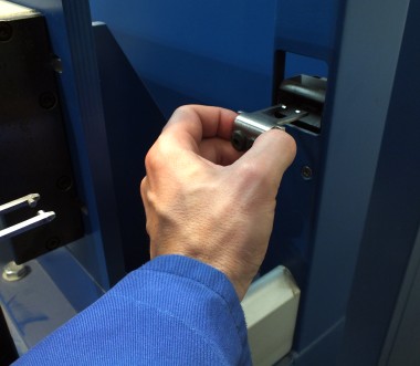 Das Bild zeigt eine menschliche Hand, die einen metallischen Gegenstand in die einen Schlitz einer Maschine schiebt. Das Bild zeigt eine menschliche Hand, die einen metallischen Gegenstand in die einen Schlitz einer Maschine schiebt.