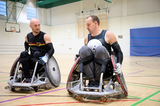 Zwei Spieler im Rugby-fähigen Rollstühlen, Sauerbach links, versucht dem anderen den Ball abzujagen.