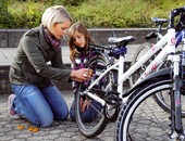 Eine Mutter repariert mit ihrer Tochter den Hinterreifen eines Fahrrads